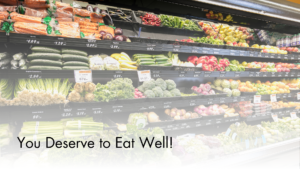 Image of the produce section at a grocery store with fruits and vegetables stocked on shelving. The words You Deserve to Eat Well are along the bottom where the image fades to white.