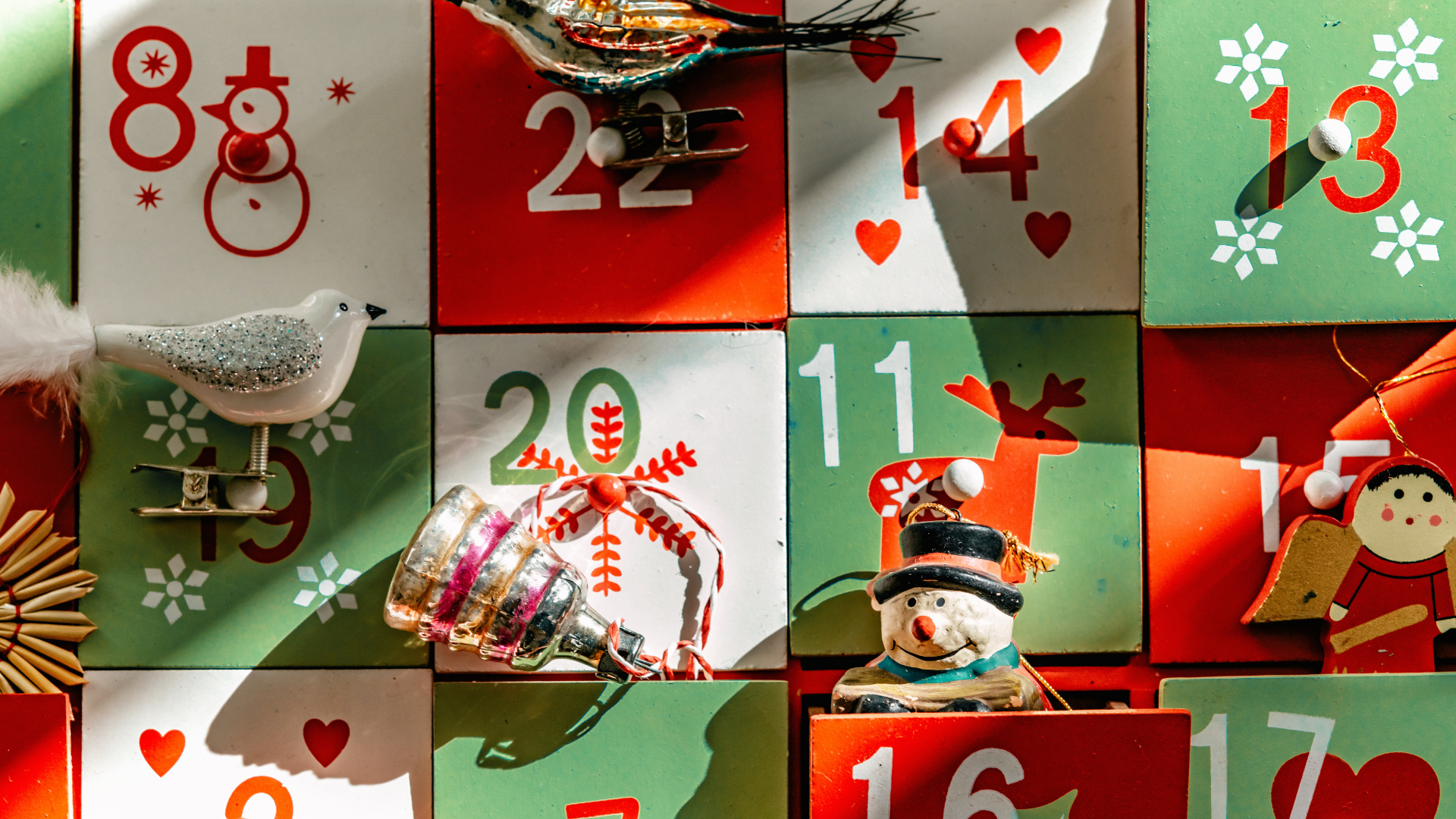 An Advent cabinet with red, white, and green drawers, and small tree ornaments coming out of some of them.